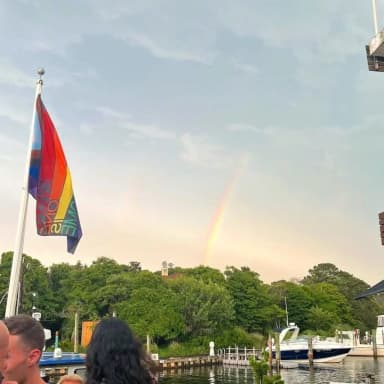 A harbor scene with a rainbow and a pride flag